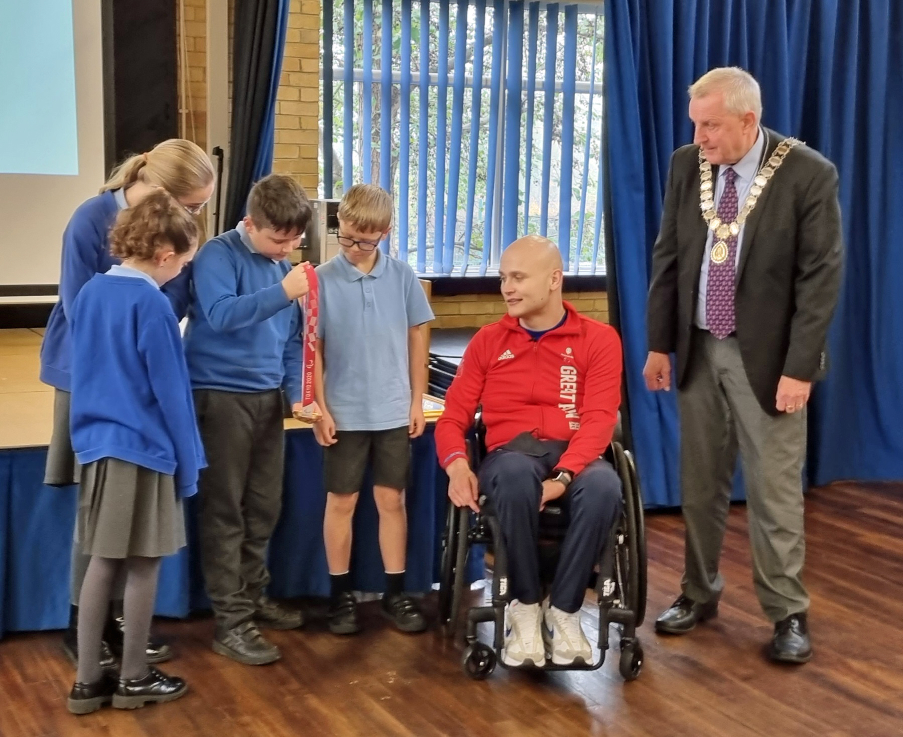 Jack Smith shows Sedgefield Primary School pupils his Paralympic gold medal, with Cllr Dave Jasper, Mayor of Sedgefield